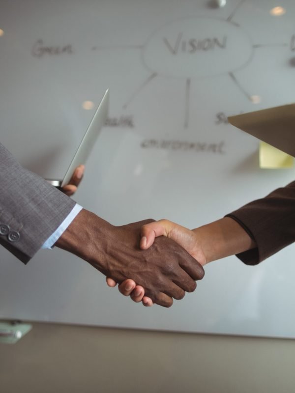 Mid section of businessman and a colleague shaking hands in office Mid section of businessman and a colleague shaking hands in office